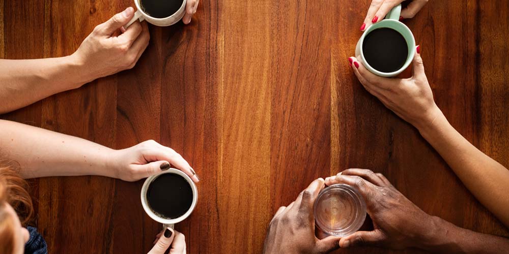People sharing coffee around a wooden table